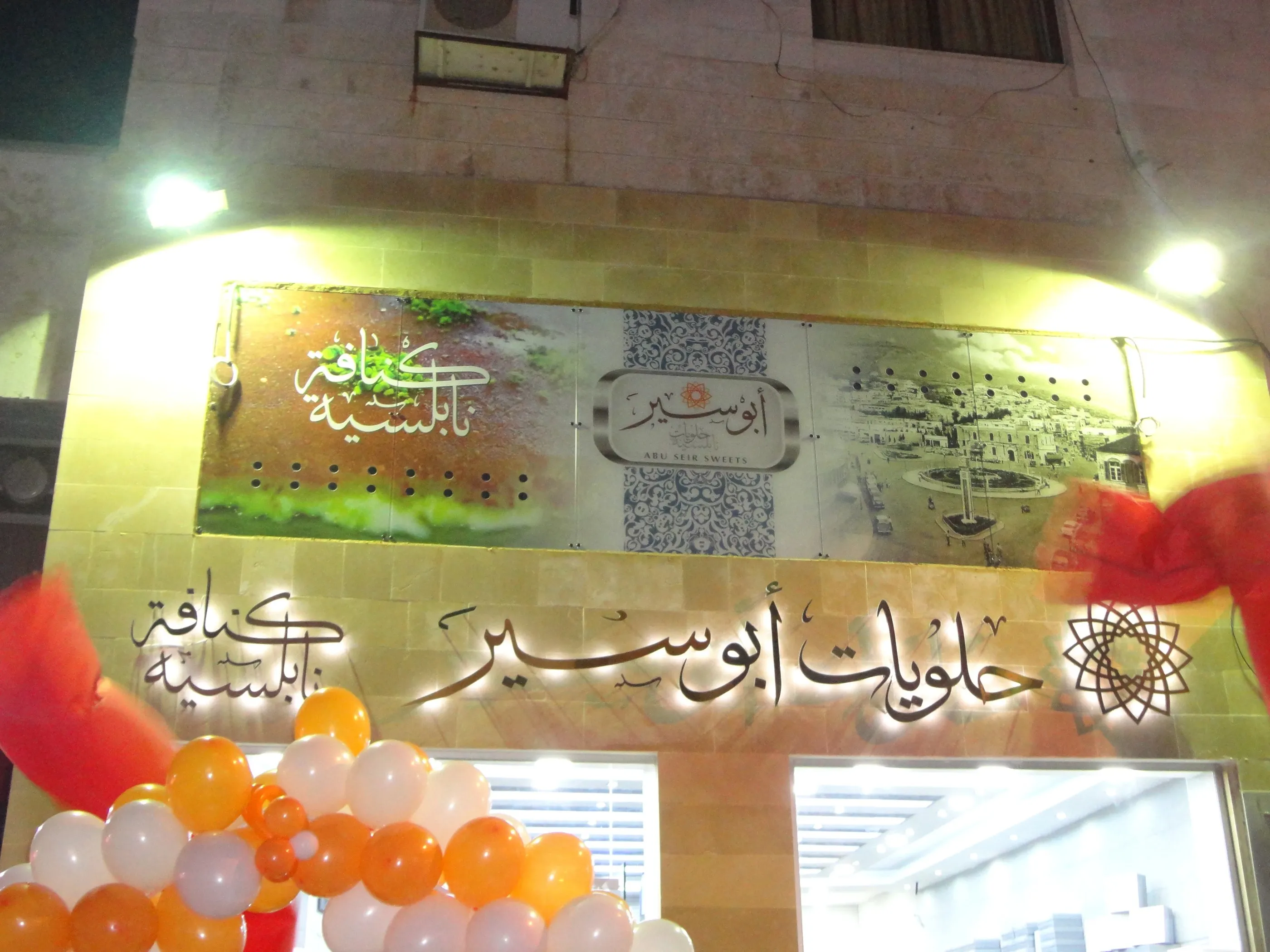 Abu Seir Sweets illuminated wall sign at night